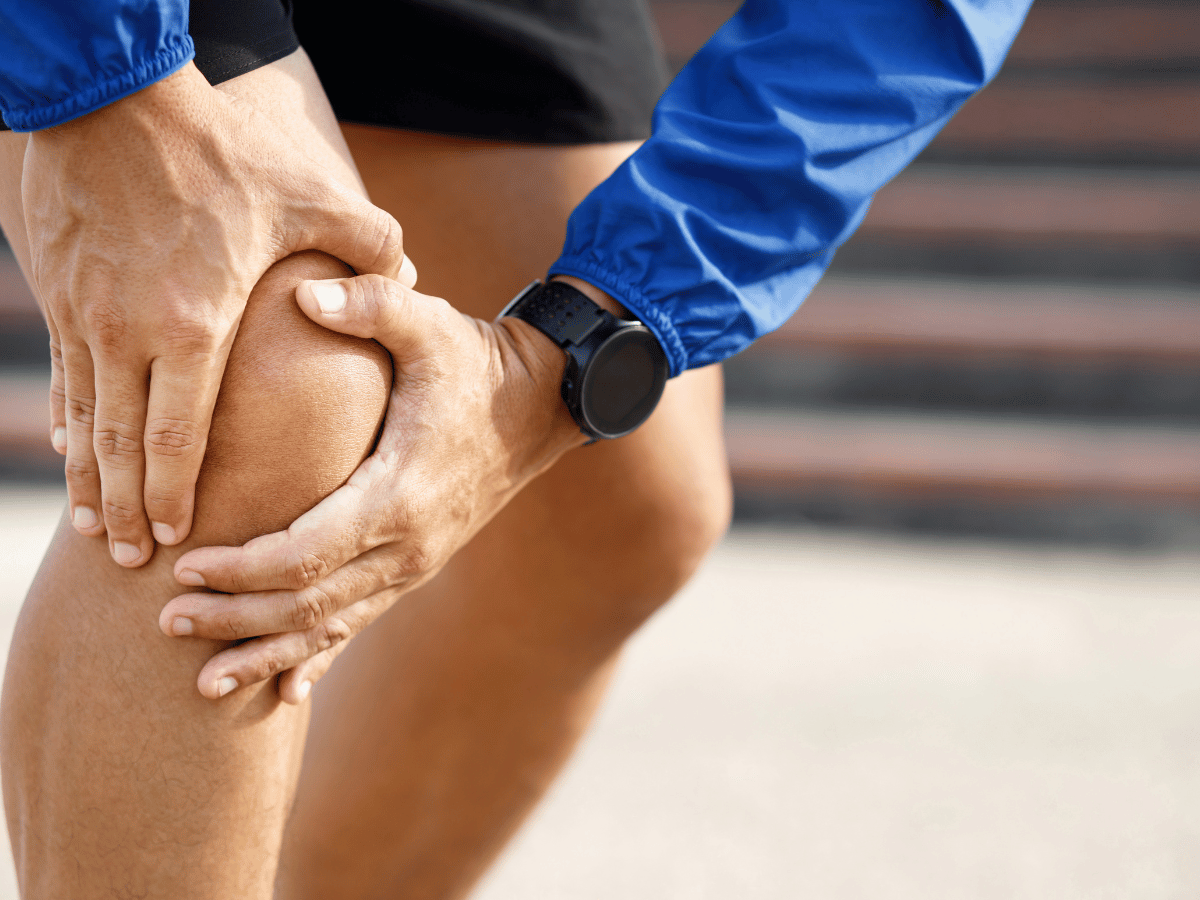 A person gripping their knee experiencing pain from a workout