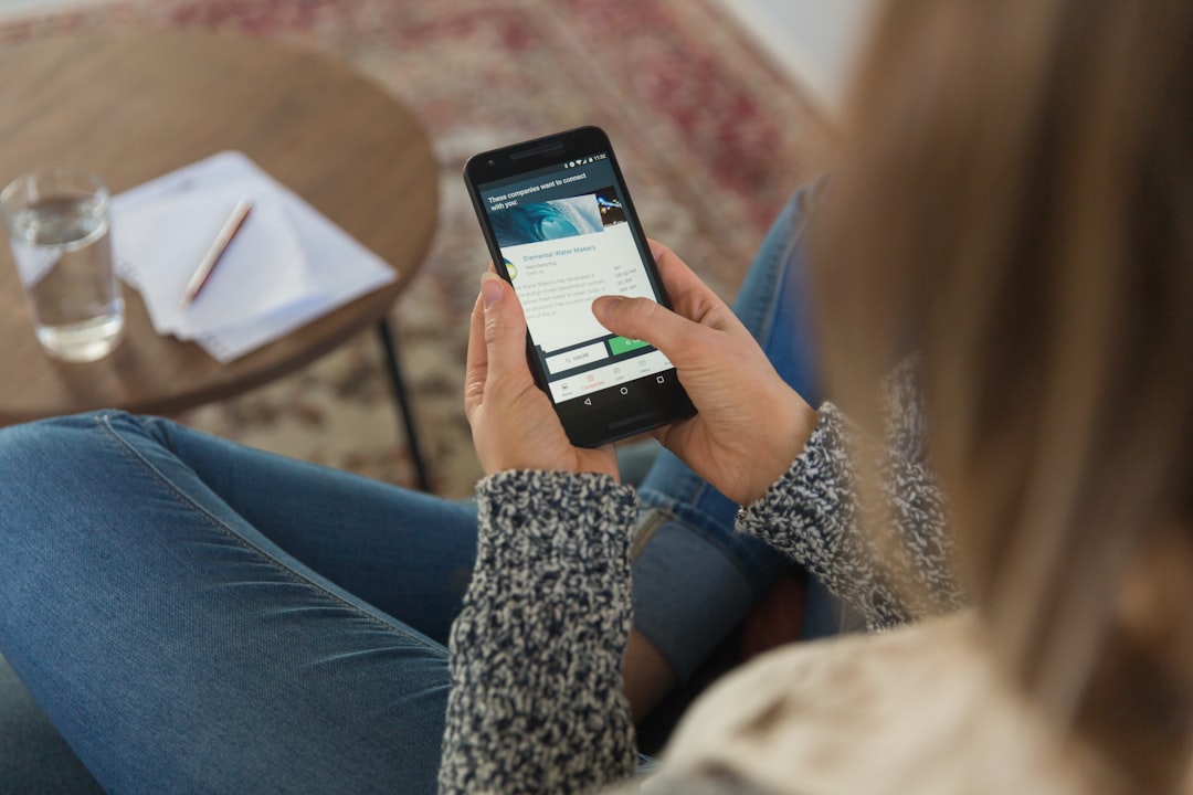 A person uses their smartphone to meticulously document water damage on an interior wall, an essential step for a successful insurance claim.