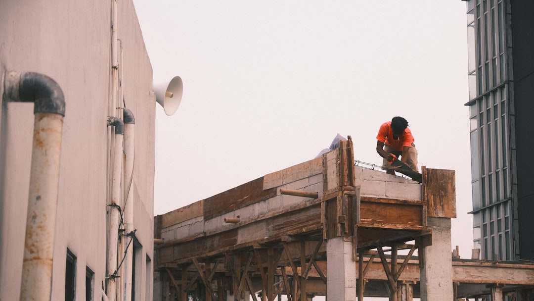 A professional roofer repairs a home's shingles on a bright, sunny day, symbolizing the hopeful process of rebuilding after a storm.