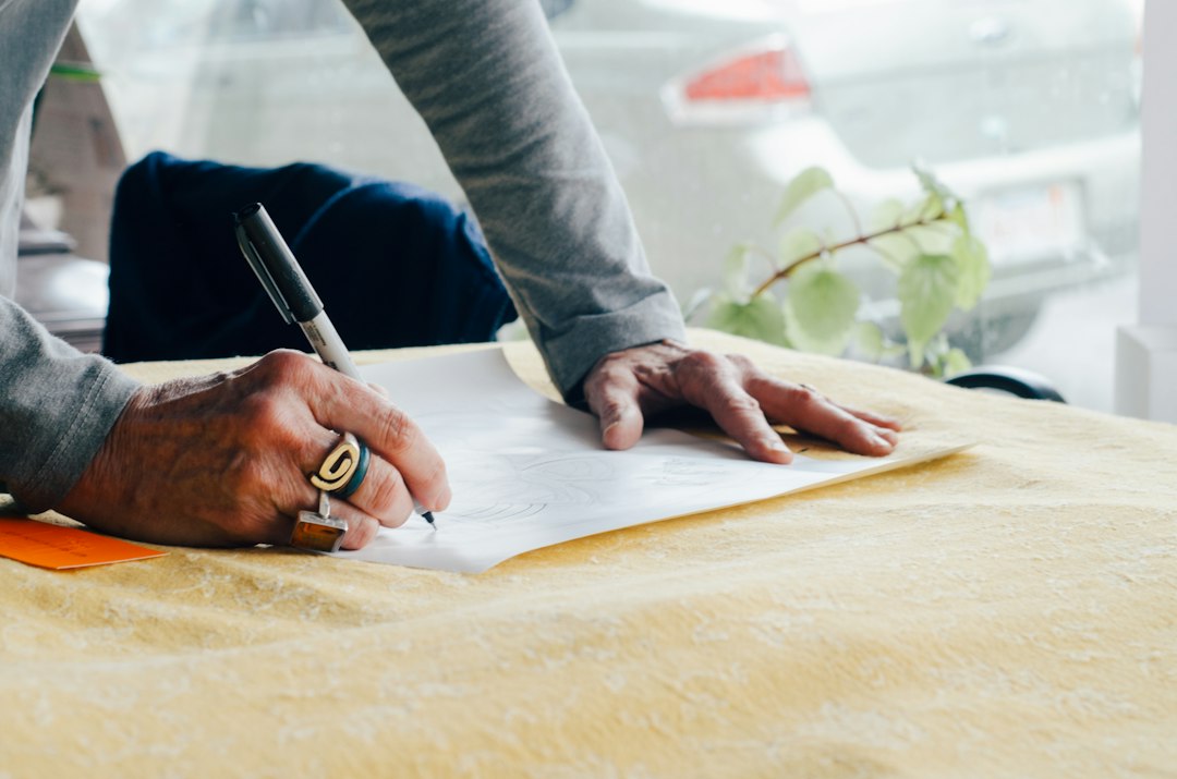 Close-up of a person's hands reviewing a real estate contract on a clean, modern desk with a calculator and pen nearby.