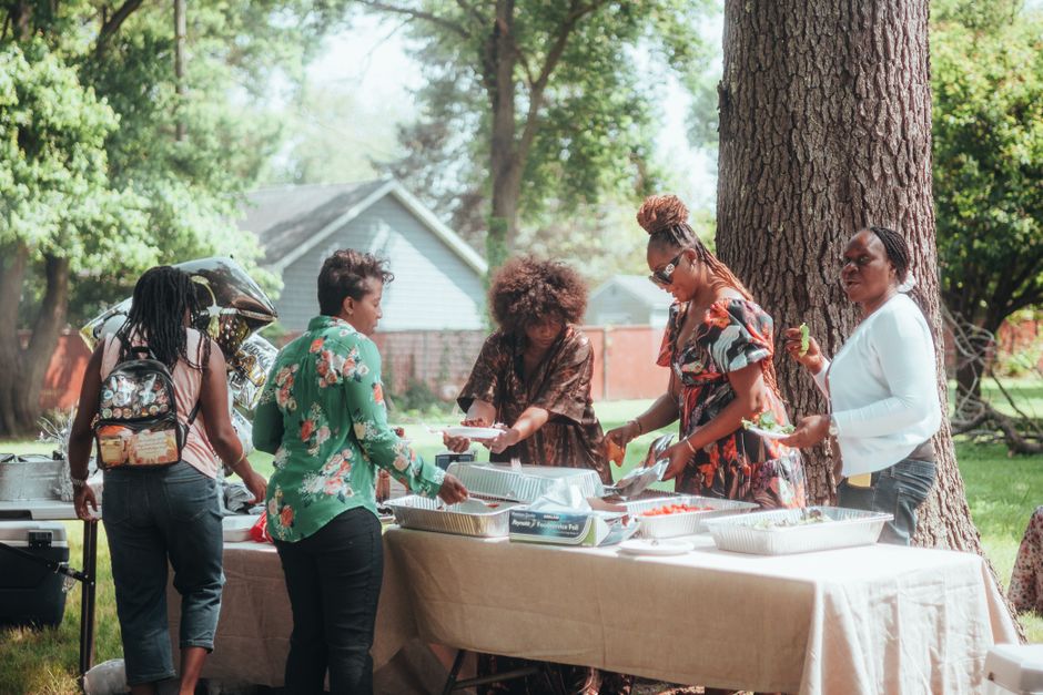 A diverse group of happy neighbors of all ages mingling and laughing together at an outdoor block party on their street, illustrating a vibrant and connected community network.